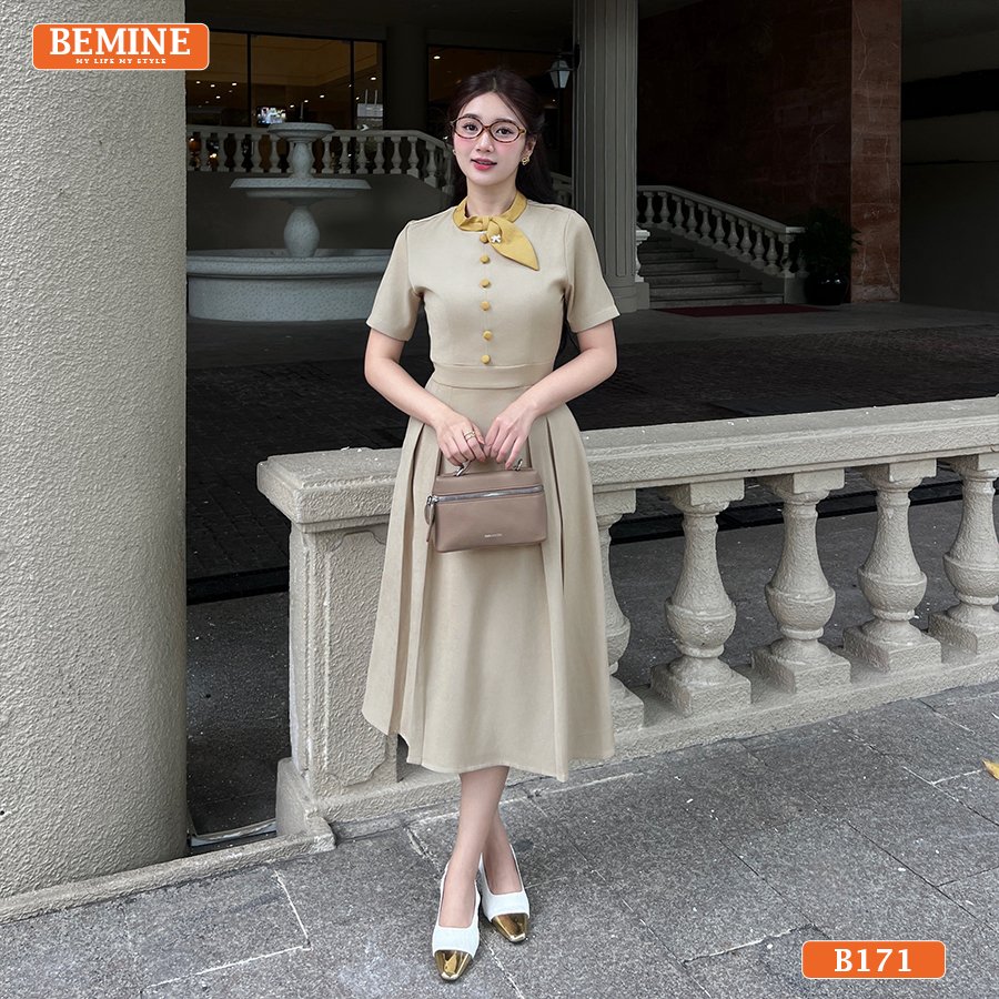 Đầm thiết kế BEMINE cổ trụ phối viền nơ đính cúc dáng chữ A phù hợp đi làm-B171 Mẫu đầm công sở BEMINE B171, nổi bật với thiết kế cổ trụ, viền tương phản và chi tiết nơ cài.