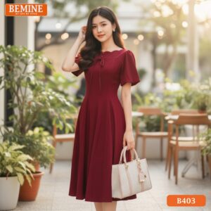 Người mẫu mặc đầm thiết kế BEMINE B403 dáng chữ A, cổ thuyền, màu đỏ, phong cách chuyên nghiệp.