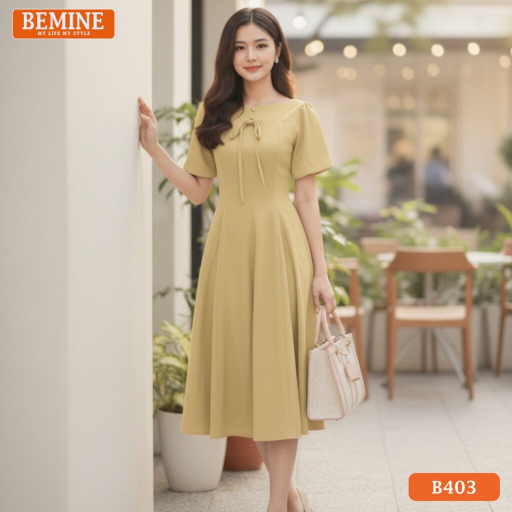 Người mẫu mặc đầm thiết kế BEMINE B403 dáng chữ A, cổ thuyền, màu vàng, phong cách chuyên nghiệp, nổi bật.